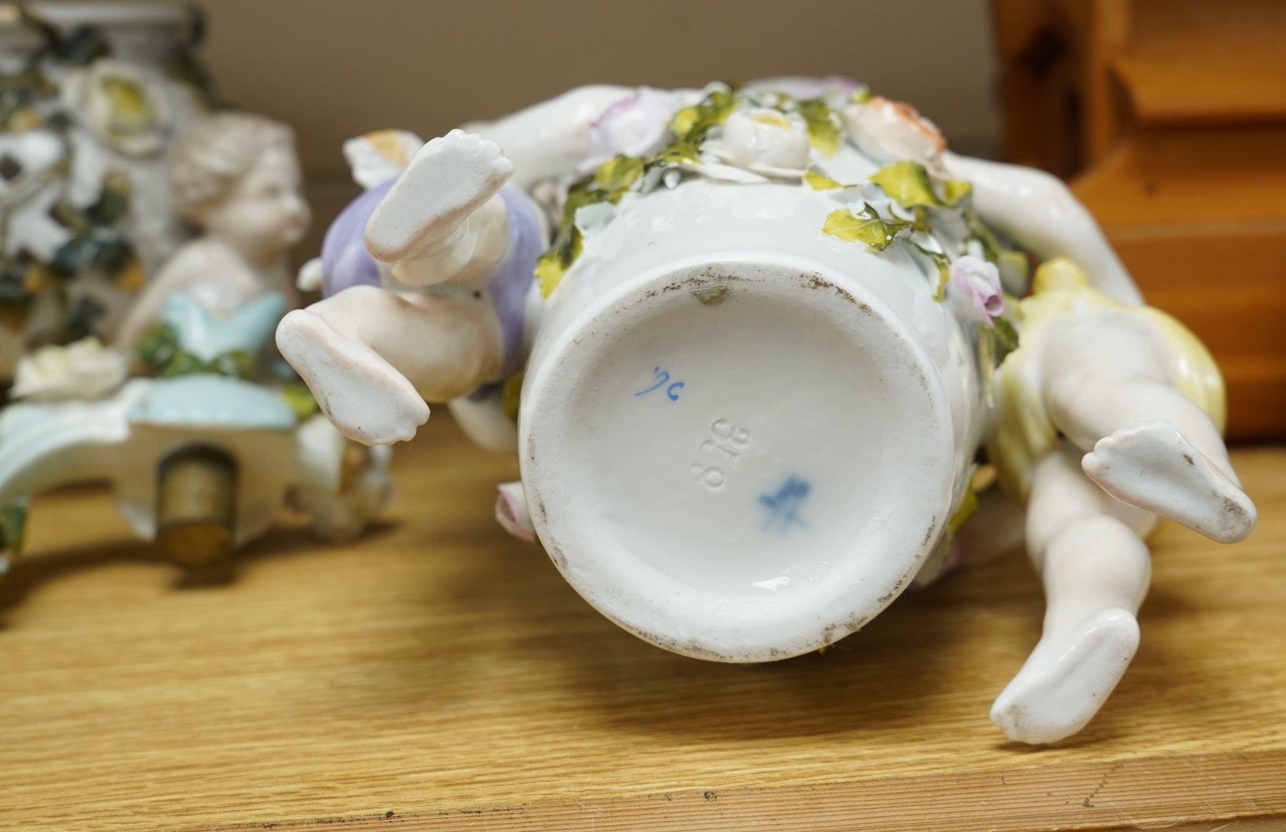 A German flower encrusted porcelain figural candelabrum, 30cm high, a cherub jardiniere and a cherub vase, all encrusted